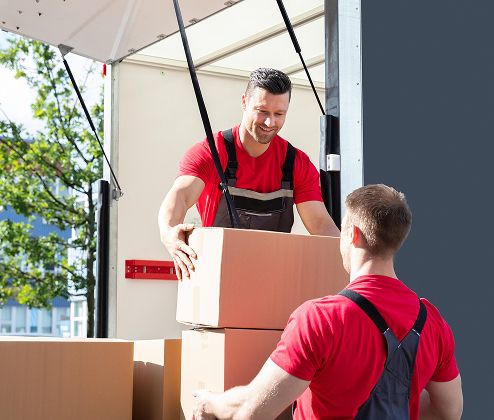 Two workers handling cartons at the back of a cargo truck